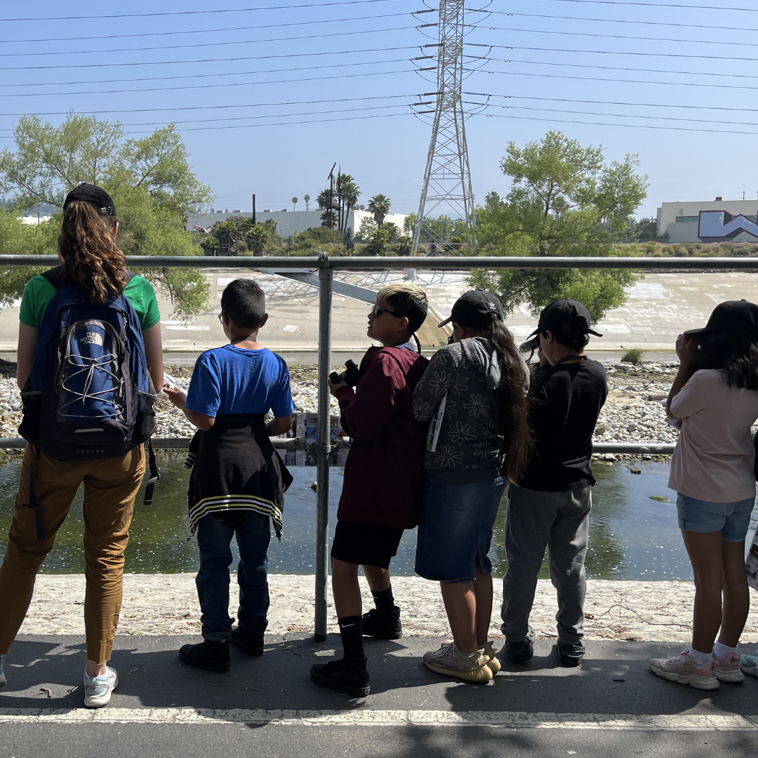 Students look at the LA River from a shaded area on the river trail.