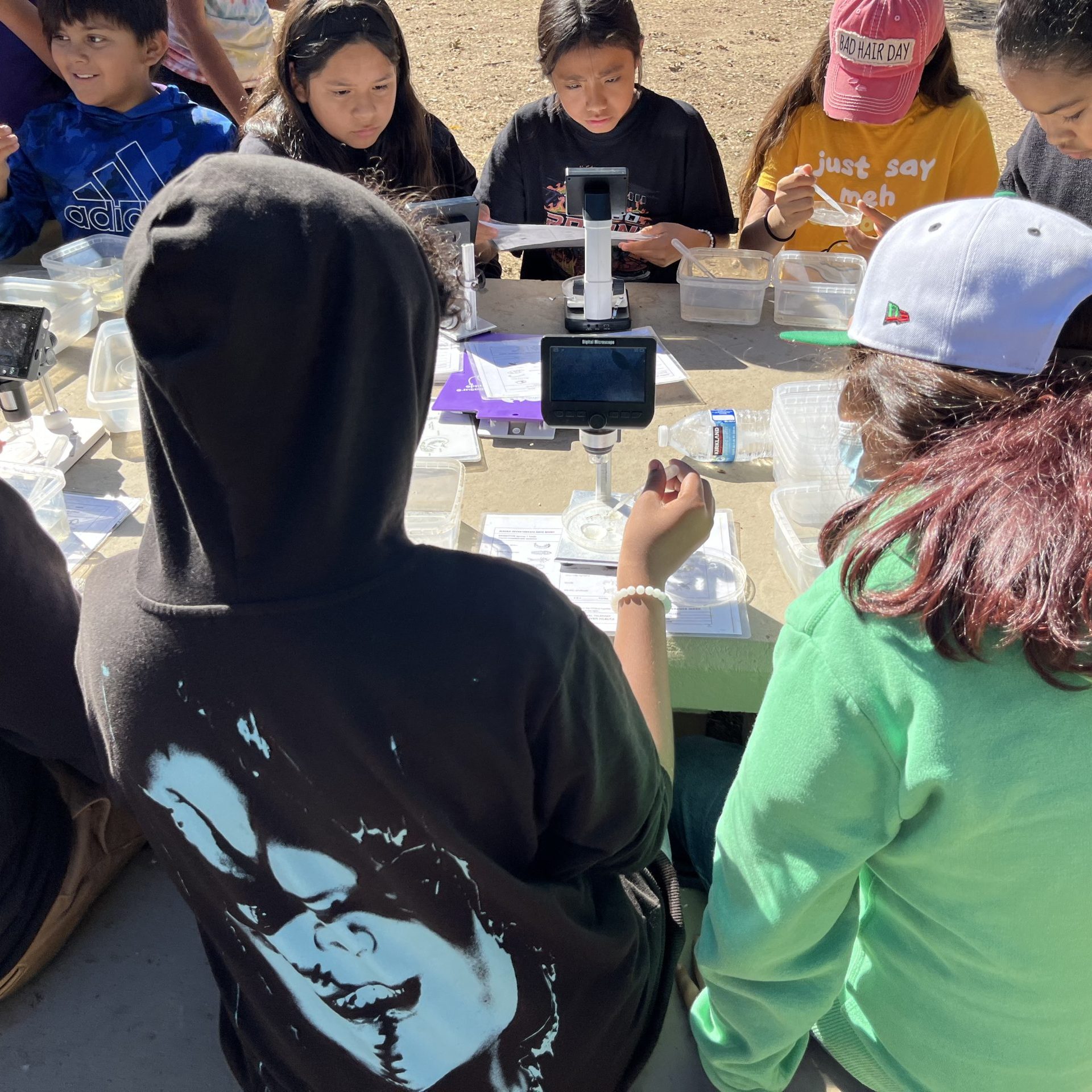 Students gathered at a table outside to work on a project.